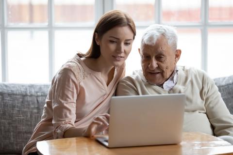 Une jeune femme aide un vieux monsieur à utiliser son ordinateur
