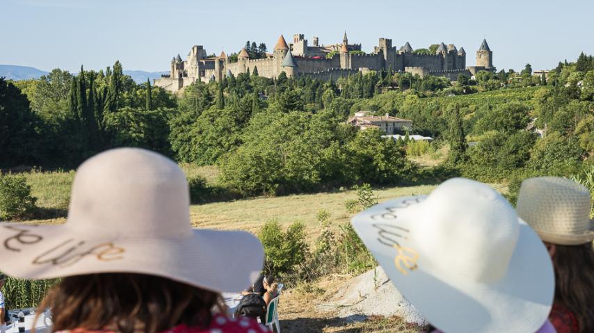 deux touristes aux chapeaux devant la cité de Carcassonne