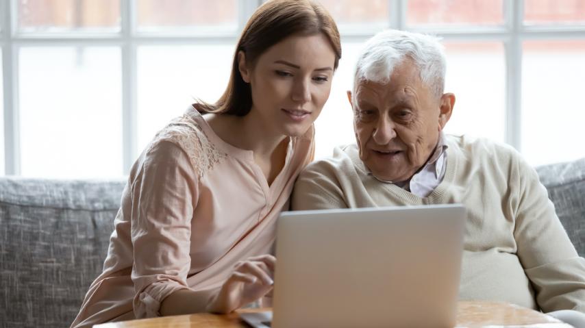 Jeune femme expliquant le fonctionnement d'un ordinateur à une personne âgée